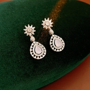 Macro shot of silver flower teardrop earrings with pink gemstones on green velvet