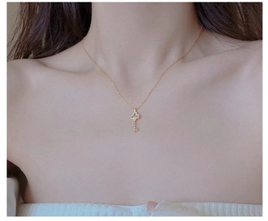 Detailed close-up of a gold-plated S925 silver key pendant with pavé crystals on a model