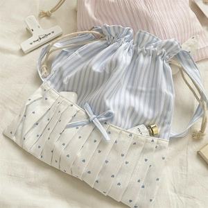 Detail of blue striped drawstring bag with heart print pocket and ribbon bow decor
