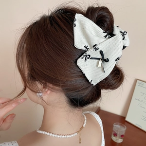 Elegant tweed bow hair claw clip with golden pendant detail on stylish bun hairstyle