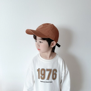 Détail d'une casquette enfant marron avec smiley et t-shirt imprimé 1976