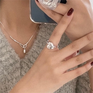 Mirror selfie showing a silver heart ring and teardrop pendant on a gray sweater