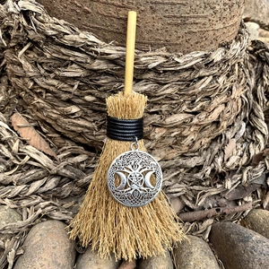 Macro view of mini witch besom broom with triple moon pentagram charm and wooden handle