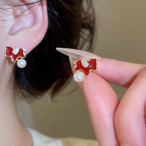 Close-up of a gold-plated horse stud earring with red enamel, rhinestones and pearls