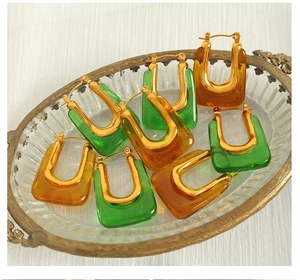 Detail of geometric U-shaped resin earrings in green and amber on a vintage tray