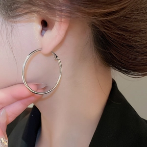 Macro detail of large silver geometric hoop earring worn by a model in a close-up shot