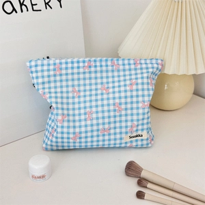 Floral makeup bag with blue plaid and pink bows shown in a cozy beauty setup