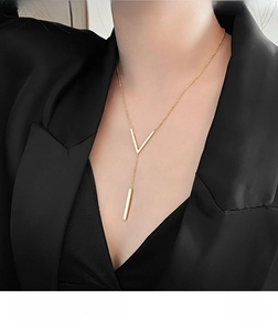 Detail of minimalist V-shaped gold titanium steel pendant necklace on black suit