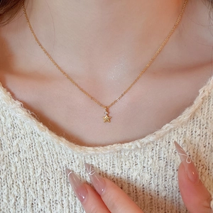 Dettaglio di una collana con ciondolo a stella dorata e zircone su un maglione morbido