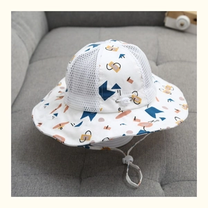 Dettaglio cappello sole neonato con rete bianca traspirante e motivi geometrici blu