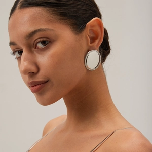 Macro detail of oversized silver round stud earrings with pave set crystal borders
