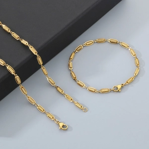 Detail of a gold rectangle link chain necklace and bracelet set on a grey background