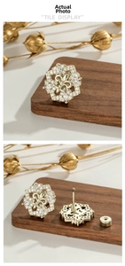 Macro detail of vintage gold hexagon stud earrings featuring fleur-de-lis and zircon pavé