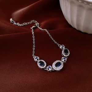 Bracelet en argent avec saphirs bleus ovales et diamants sur un fond en soie rouge chic