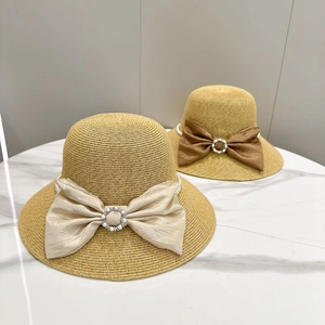 Detail of paper straw sun hats with pearl buckle and elegant large satin bows