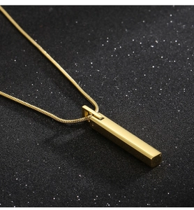Detailed view of a sleek golden bar pendant on a snake chain against a dark background