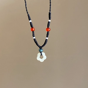 Close-up of handmade woven necklace with green flower pendant and colorful bead details