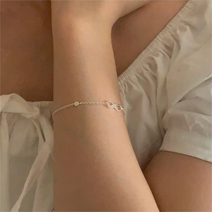 Macro detail of silver infinity bracelet with small zircons worn on a female wrist