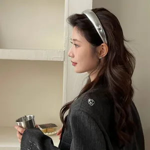 Close-up of a silver matte hairband featuring a small delicate metal heart ornament