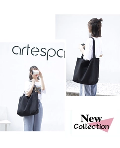 Minimalist black canvas tote bag shown with model front and side view in studio