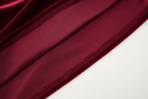 Close-up of high-quality burgundy velvet fabric and neat stitching on dress hemline