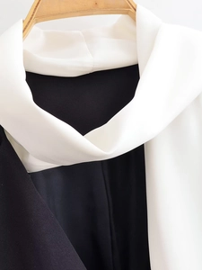 Detailed close-up of a black and white contrast scarf collar on a woven suit jacket
