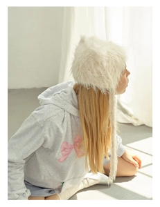 Detailed view of plush white faux fur trapper hat with long ear flaps and soft texture