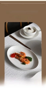 Close-up of embossed white ceramic dinnerware set with oval fish plate and rice bowl