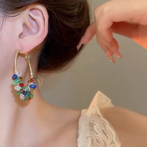 Close-up of golden hoop earrings with colorful crystal beads worn by a model