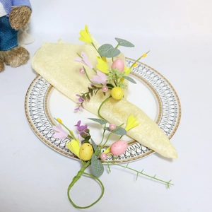 Close-up of Easter egg napkin ring with yellow flowers and berries on a gold-rimmed plate