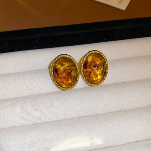 Macro shot of irregular amber resin earrings with textured gold-plated edges in box