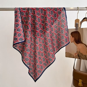 Macro detail of red paisley square scarf hanging on a metal rod with vintage props