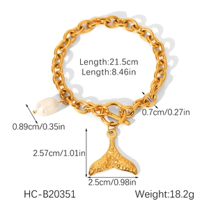 Detail of gold chain bracelet featuring a freshwater pearl and textured fishtail charm