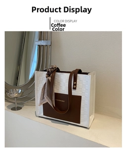 Detail of white woven tote bag with coffee leather handles and silk scarf accent