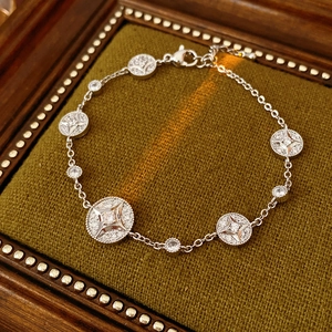 Detailed view of silver starburst charm bracelet with cubic zirconia on green velvet
