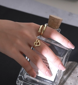 Detailed close-up of a stacked golden heart ring and a spiral band on a woman finger
