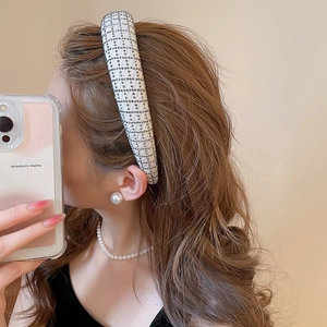 Detail shot of white padded headband featuring grid-patterned dark rhinestones and soft fabric