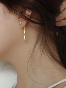 Detail of 925 silver pearl drop earrings showing elegant fit and golden metallic luster