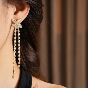 Primo piano di orecchini a fiocco placcati oro 18K con nappe in zircone su modella