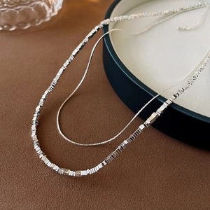 Details einer silbernen Doppelkette mit feiner Schlangenkette und geometrischem Perlendesign