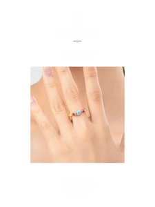 Dettaglio anello con perline colorate e ciondolo a forma di fiore azzurro da donna