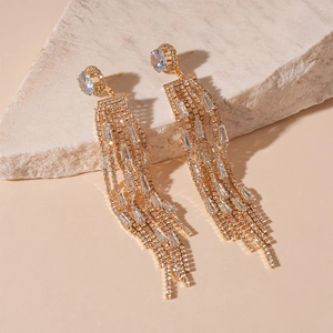Macro detail of luxury champagne gold tassel earrings with blue zircon stones on stone background