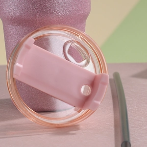 Close-up of pink glitter tumbler with transparent slider lid and dark reusable straw