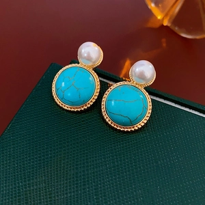 Detail of vintage gold-rimmed turquoise earrings with pearl accent on green leather box