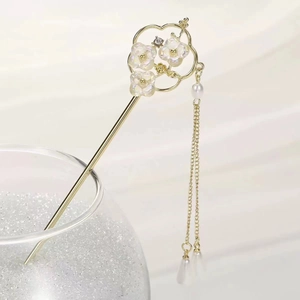 Detail of a vintage-style golden hair stick with a magnolia flower and silk tassels