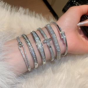 Détail de bracelets argentés sertis de zircons brillants sur fond en peluche blanche