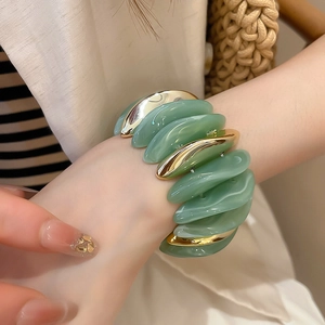 Detail of sage green acrylic and gold metal stretch bracelet on model's wrist