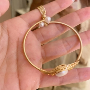 Detailed macro view of gold-plated wire-wrapped bracelet with fresh water pearls
