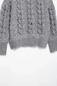 Detailed view of grey cable-knit texture and ribbed cuffs on a chunky knit sweater