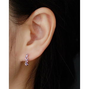 Detail of silver U-shaped earring with purple zircon stones worn by a model